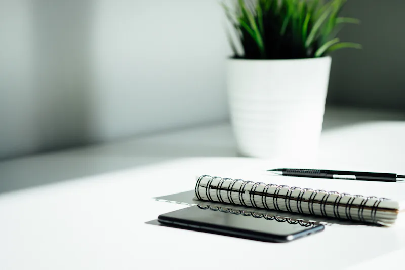 Arbeitsplatz mit Notizbuch, Stift und Smartphone
